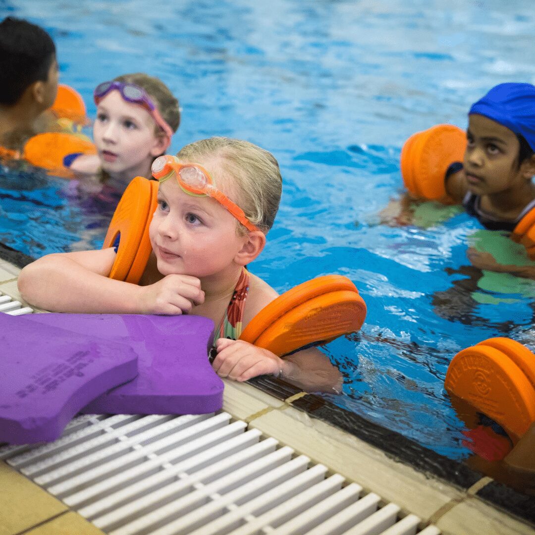 Children in a swimming lesson with floats.